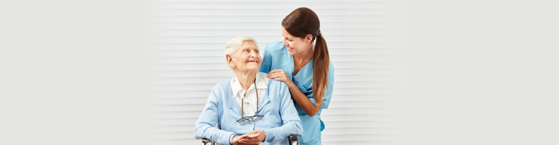 Smiling senior citizen in wheelchair and nurse