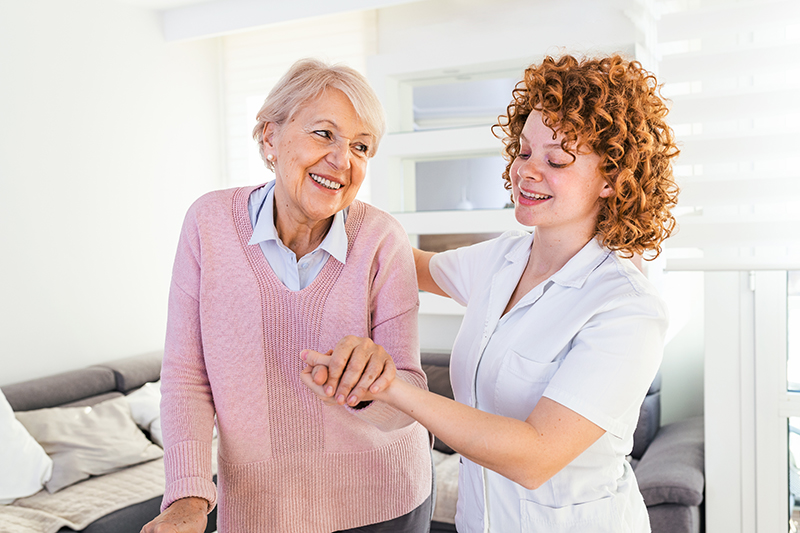 happy senior woman getting assistance from caregiver