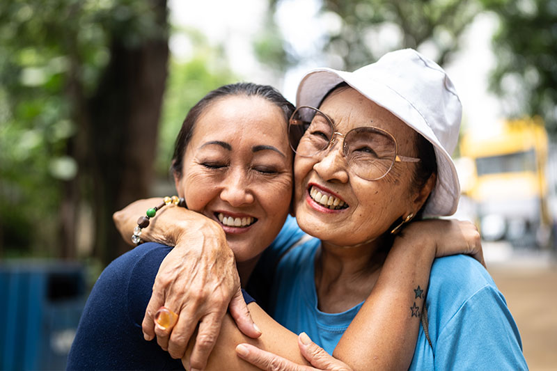 Two women hug and show support, a key aspect of communicating with compassion in dementia care. 